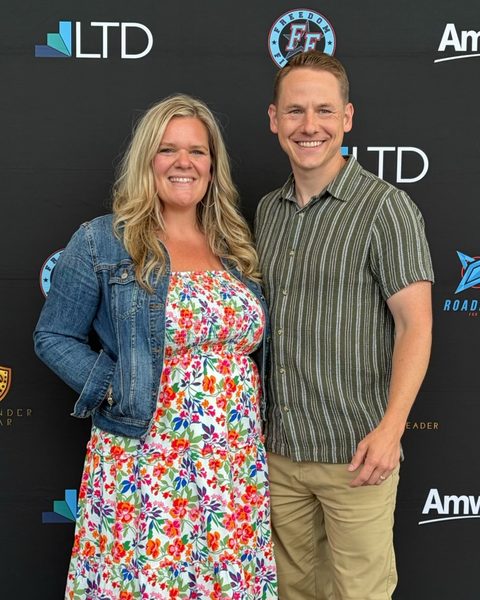 Zac and Ashley Gerard standing together in front of an event backdrop